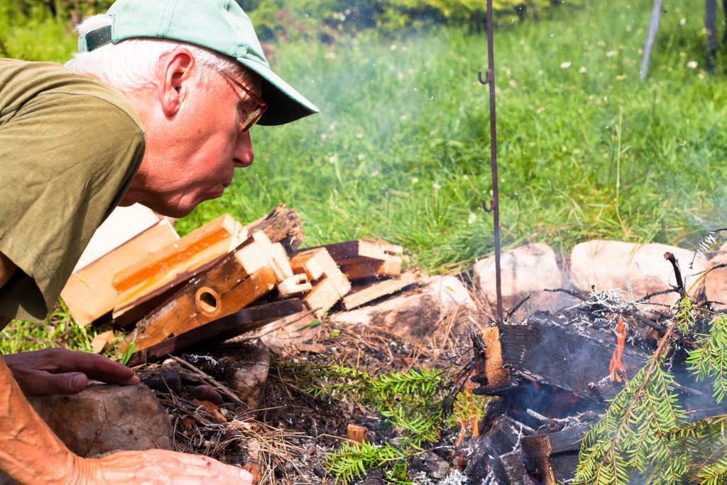 Detail of elderly man making bonfire.